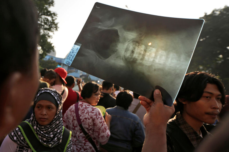 Un hombre sostiene una radiografía para ver el eclipse en Yakarta, Indonesia. Foto: Dita Alangkara/AP